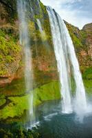 Beautiful, with cave inside Seljalandsfoss waterfall in South Iceland, summer time photo