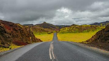panorámico terminado un pavimentado la carretera y dramático islandés vistoso y salvaje paisaje a verano tiempo, Islandia foto