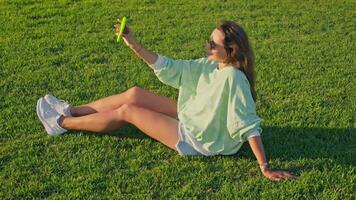 fille prend selfie séance sur le herbe video