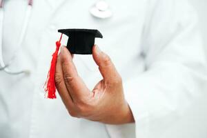 Asian woman doctor holding graduation hat in hospital, Medical education concept. photo