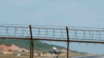 PHUKET, THAILAND JANUARY 22, 2023 - Passenger aircraft Airbus A320 of VietJet take off at Phuket airport. Airliner fly overhead. View from the ends of the runway, through the fence. Travel concept video