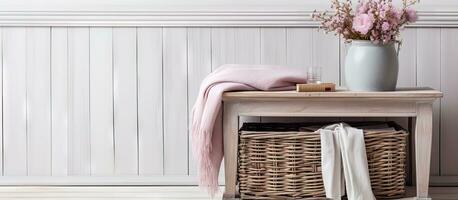 Selective focus on oak side table with wicker basket pink scarf dried flowers book and cup against white wooden wall photo