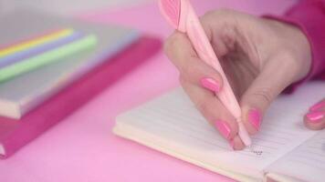 Girl writing on diary on pink background with pink nails video