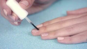 Painting pink nails on blue glitter background video