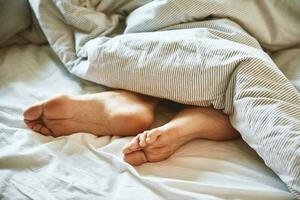 Female legs in the bed under blanket photo