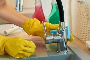 Woman cleaning kitchen sink with water tap photo