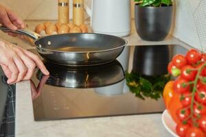 Woman turn on induction hob with frying pan photo