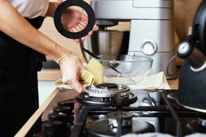 mujer limpieza gas estufa en cocina interior foto