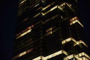 alto subir oficina edificio con iluminado ventanas a noche foto