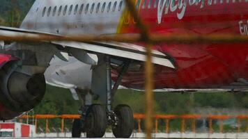PHUKET, THAILAND NOVEMBER 26, 2016 - Passenger Vietnamese airliner VietJet taxiing at Phuket airport. View of the chassis and engines of the aircraft through the fence. Tourism and travel concept video