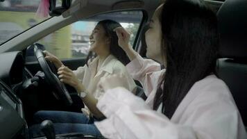 dos asiático mujer escucha a música y conducir un coche. contento y mujer bailando en el coche escuchando a el radio. estilo de vida y viaje concepto. video