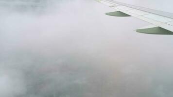 View from the window on the wing of the aircraft in the clouds. Airliner descent, porthole video