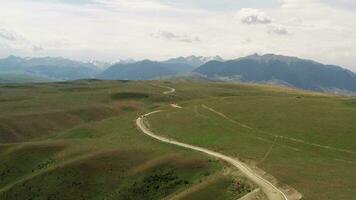 Mountain peaks and grassland are under white clouds. video