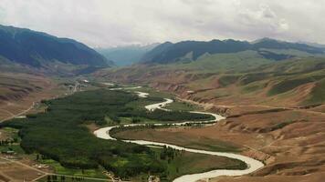 Mountain peaks and grassland are under white clouds. video