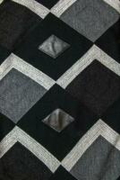 Detailed inserts in black genuine leather on a knitted woolen background with an abstract pattern. Abstract fabric texture. photo