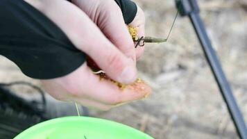 The fisherman puts fish food in the feeder. Close-up of the hands of an unrecognizable fisherman preparing the bait for the fish. The concept of lifestyle, leisure in nature. The guy cooks fish food. video