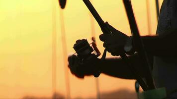 pescador recuperación pescar línea con carrete a puesta de sol. navegar fundición video