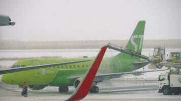 novosibirsk, ruso federación junio 10, 2020 - s7 aerolíneas abrazador 170 antes de tomar apagado. aeronave deshielo, antihielo con anticongelante antes de quitarse durante fuerte tormenta de nieve video