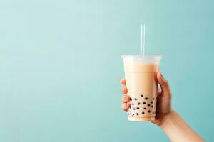 A hand holding takeaway plastic cup of delicious iced bubble milk tea and black pearls with copy space. ai generated photo