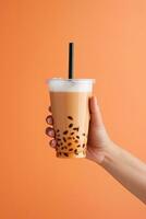 A hand holding takeaway plastic cup of delicious iced bubble milk tea and black pearls. ai generated photo