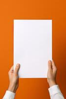 A human hand holding a blank sheet of white paper or card isolated on orange background. ai generated photo