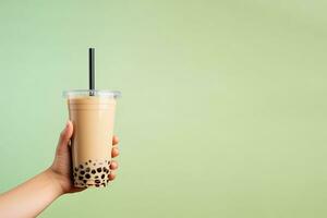 A hand holding takeaway plastic cup of delicious iced bubble milk tea and black pearls with copy space. ai generated photo