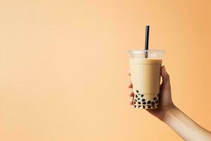 A hand holding takeaway plastic cup of delicious iced bubble milk tea and black pearls with copy space. ai generated photo