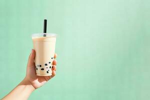 A hand holding takeaway plastic cup of delicious iced bubble milk tea and black pearls with copy space. ai generated photo