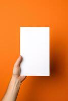 un humano mano participación un blanco sábana de blanco papel o tarjeta aislado en naranja antecedentes. ai generado foto