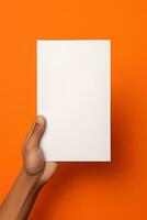 A human hand holding a blank sheet of white paper or card isolated on orange background. ai generated photo