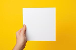 A human hand holding a blank sheet of white paper or card isolated on yellow background. ai generated photo