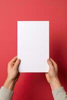 A human hand holding a blank sheet of white paper or card isolated on red background. ai generated photo