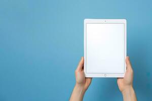 Hand holding tablet with mockup blank screen isolated on blue background with copy space. ai generated photo
