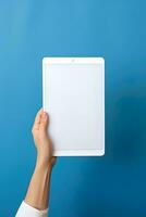 Hand holding tablet with mockup blank screen isolated on blue background. ai generated photo