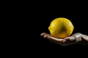 Lemon in hand isolated on black background with copy space. ai generated photo