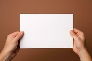 A human hand holding a blank sheet of white paper or card isolated on brown background. ai generated photo