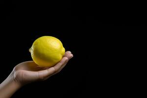 Lemon in hand isolated on black background with copy space. ai generated photo