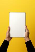 Hand holding tablet with mockup blank screen isolated on yellow background. ai generated photo