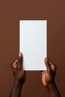 A human hand holding a blank sheet of white paper or card isolated on brown background. ai generated photo