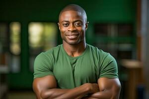 sonriente joven negro hombre soportes en frente de verde fondo con doblada brazos y verde camisa foto