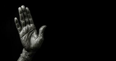 Hand on black with space for text. Hands of a man in a silver glove on a black background. photo