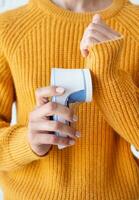 woman in yellow sweater using fabric pills removing tool photo