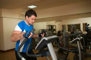 hombre hacer ejercicio en elíptico máquina en gimnasio foto