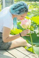 joven mujer con hermosa azul rastas descansando en loto lago foto