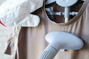 Close up of female hand with vertical steamer and tshirt photo