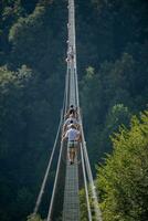 People while crossing the Tibetan bridge of Dossena.Which is the longest in the world photo