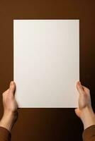 un humano mano participación un blanco sábana de blanco papel o tarjeta aislado en marrón antecedentes. ai generado foto