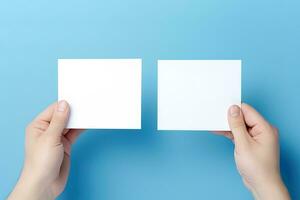 A human hand holding a blank sheet of white paper or card isolated on blue background. ai generated photo