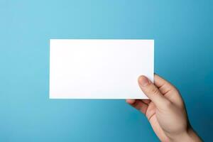 A human hand holding a blank sheet of white paper or card isolated on blue background. ai generated photo