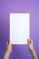 A human hand holding a blank sheet of white paper or card isolated on purple background. ai generated photo